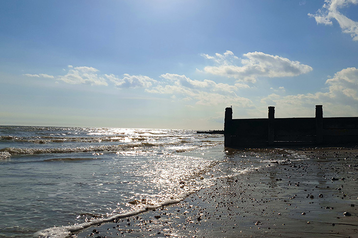 Beach, sea and groyne at low tide (on a sunny day) on the beach looking west